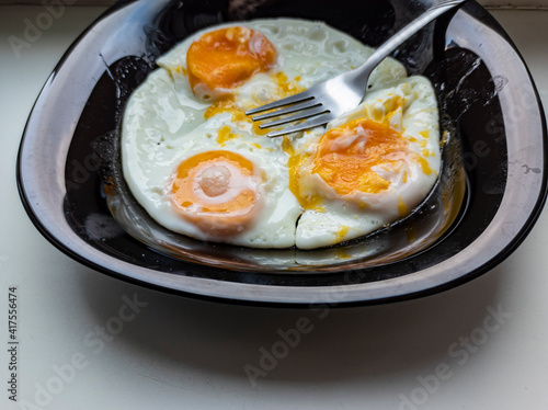 Obraz na płótnie photo of fried eggs in a black plate on a white background. food photo w salonie