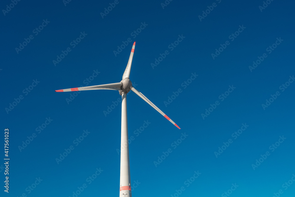 Big wind turbine to generate electrical power as green ecofriendly energy at blue deep sky and copy space for text.
