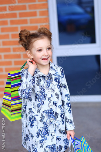 A girl with a lot of packages in her hands. The child has a lot of bags after the store. Children and shopping