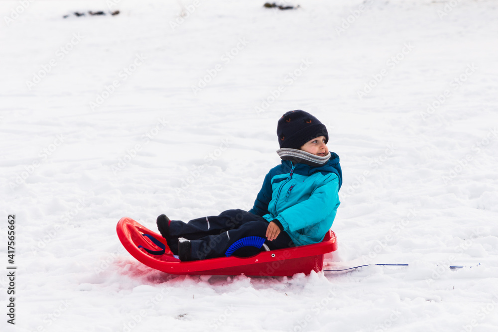 boy with red sled in the snow boy with red sled in the snow