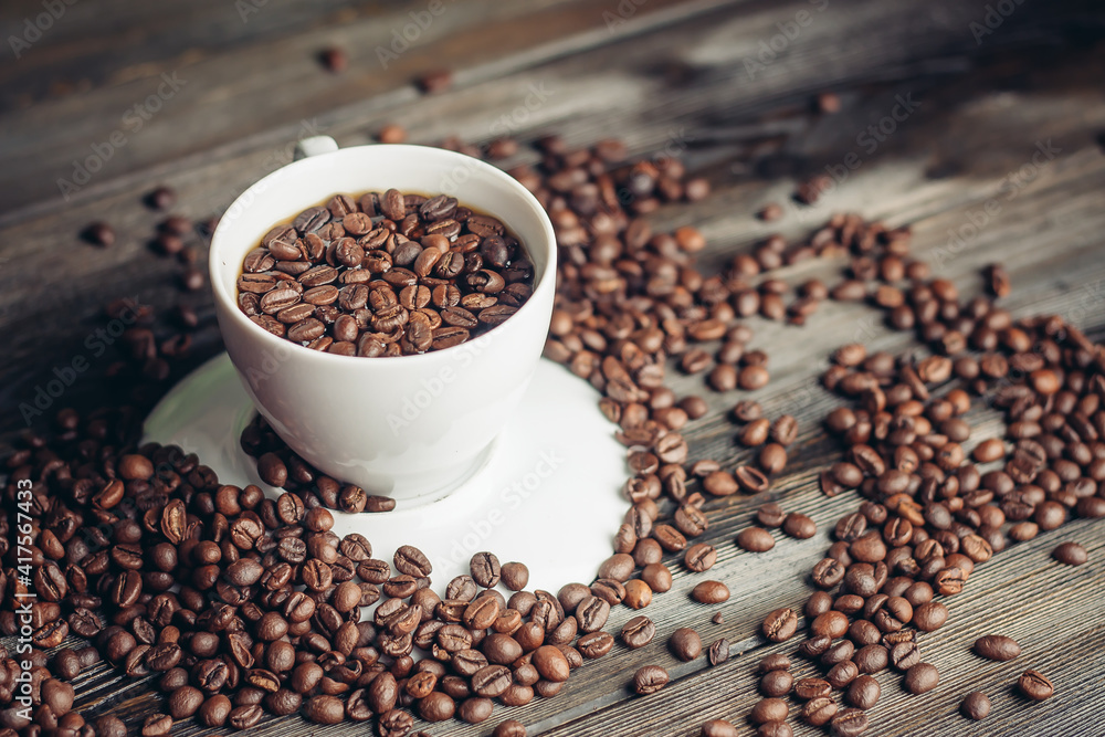 coffee beans on a wooden background and a cup on a saucer close-up macro photography coffee beans on a wooden background and a cup on a saucer close-up macro photography