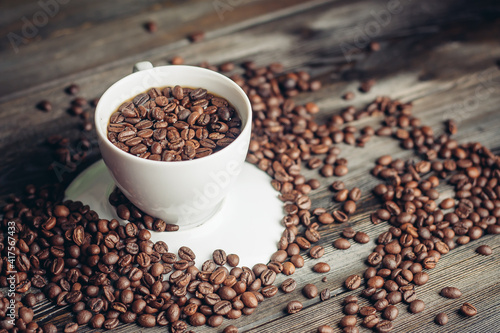 coffee beans on a wooden background and a cup on a saucer close-up macro photography