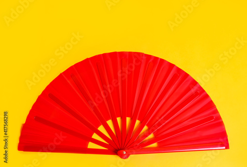 Red hand fan on yellow background  top view