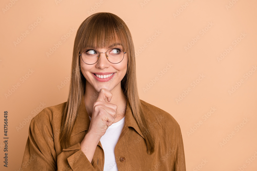 Photo of minded dreamy young woman look empty space hold hand chin think isolated on beige color background Photo of minded dreamy young woman look empty space hold hand chin think isolated on beige color background