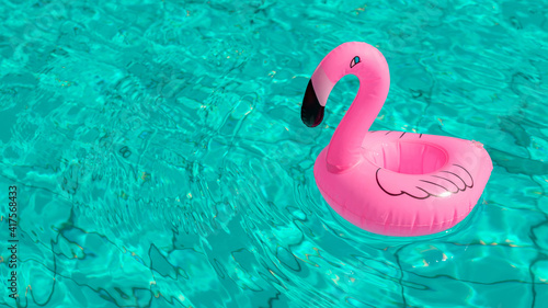 Beach flamingo. Pink inflatable flamingo in pool water for summer beach background. Trendy summer concept.