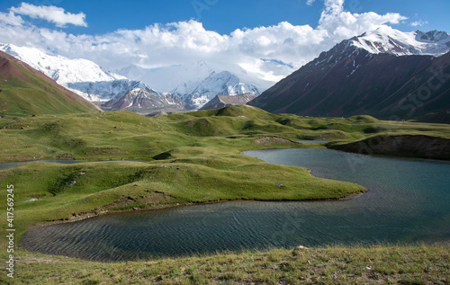 landscape with lakes and mountains in green valley under bright sun 