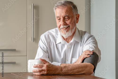 Caucasian old man measure blood pressure. Background neutral color
