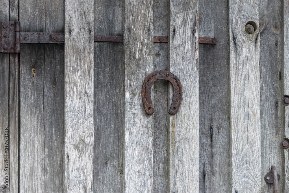Symbol of success. A metal horseshoe hangs at natural wood door. Symbol of success. A metal horseshoe hangs at natural wood door.