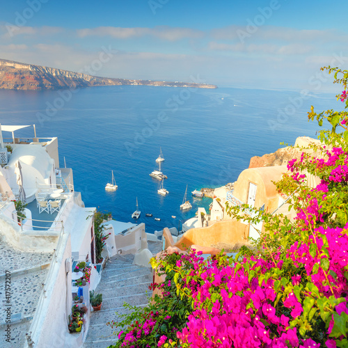 Fototapeta Naklejka Na Ścianę i Meble -  Old street with flowers, traditional Greek houses and a staircase to the sea, Santorini, Greece