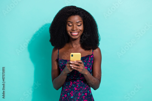 Photo portrait woman smiling typing message on mobile phone texting isolated bright teal color background