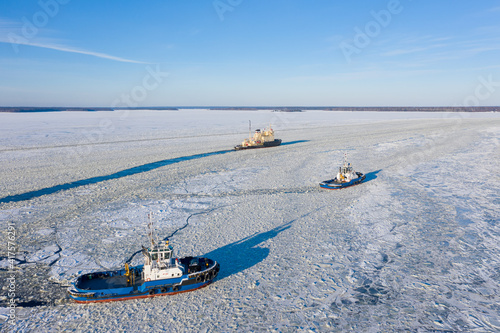 Ships sailing on a frozen sea in winter conditions aerial photography. The coastline is on the horizon.