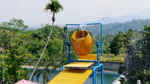 Barrel fountain by swimming pool, creative decoration in exotic water park photo
