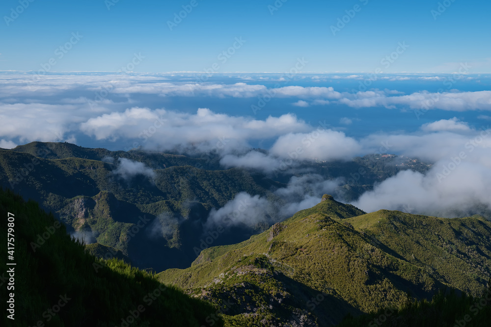 Above the clouds on a mountain trail. Colorful mist in valley. Trekking from Pico do Arieiro to Pico Ruivo, Madeira island, Portugal. 