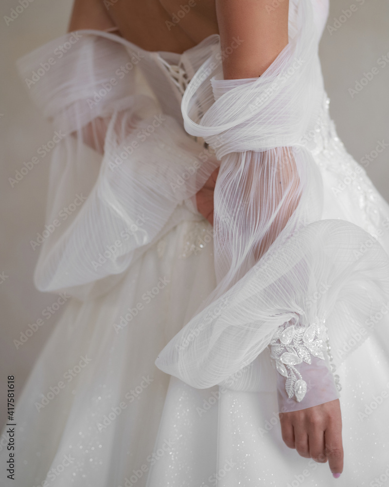 White bridal dress close-up. Bride hands. wedding details. Elegant woman posing, Slim female model. Stylish fashionable woman.