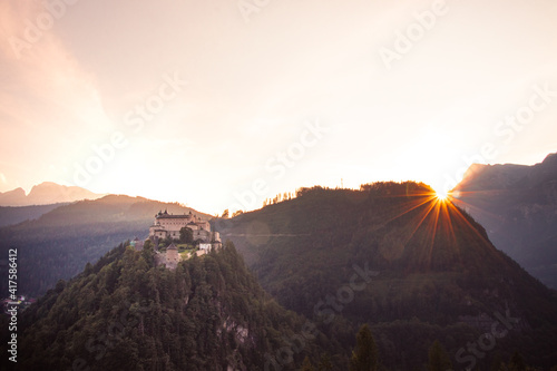 medieval Hohenwerfen Castle towering over the Austrian town of Werfen at sunset turns pink-orange. Guard castle before the invasion of enemies. The sun shines through the castle photo