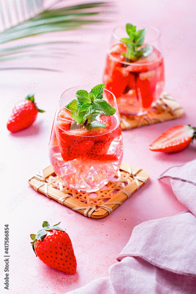 Summer mint and strawberry infused water on pink table top, still life, top view. Summer fruity refreshing cocktail still life closeup Summer mint and strawberry infused water on pink table top, still life, top view. Summer fruity refreshing cocktail still life closeup