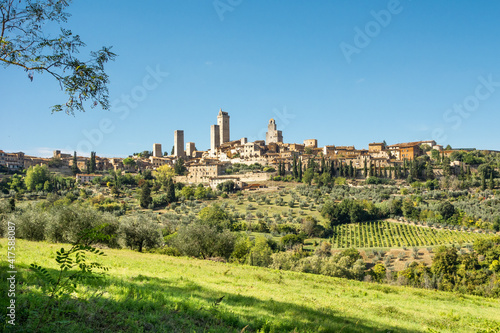 Panoramic view of San Gimignano, Tuscany., with olive orchards  and cypress trees under a blue sky