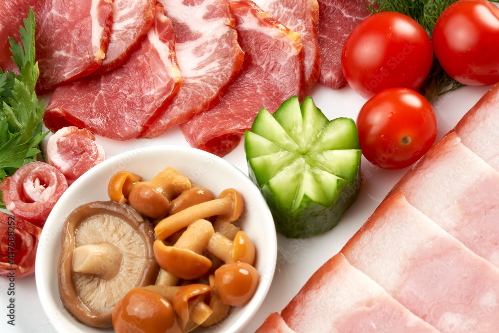 Assorted ham with cherry tomatoes, cucumbers and mushrooms on a platter. Close-up