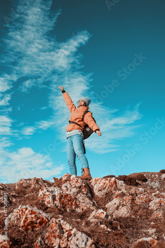 Cheering woman backpacker enjoy the view on sunrise mountain top cliff edge