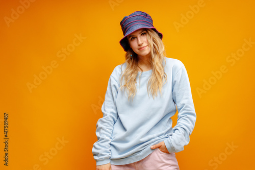 Portrait of a young woman hipster wearing panama hat against yellow background