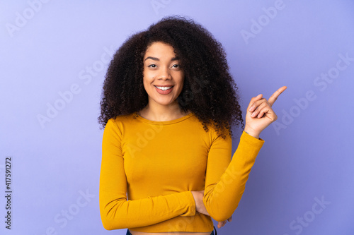 Young african american woman isolated on purple background happy and pointing up