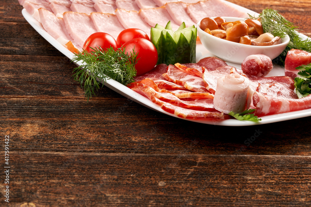 A plate of deli meats, garnished with cherry tomatoes, mushrooms and herbs, parsley. Copy space