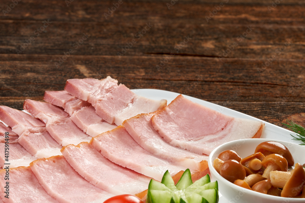 Ham on a plate, still life on a wooden natural background.