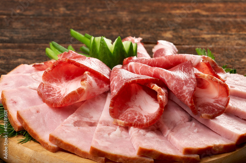 Pieces of appetizing coppa on a wooden background, still life composition.