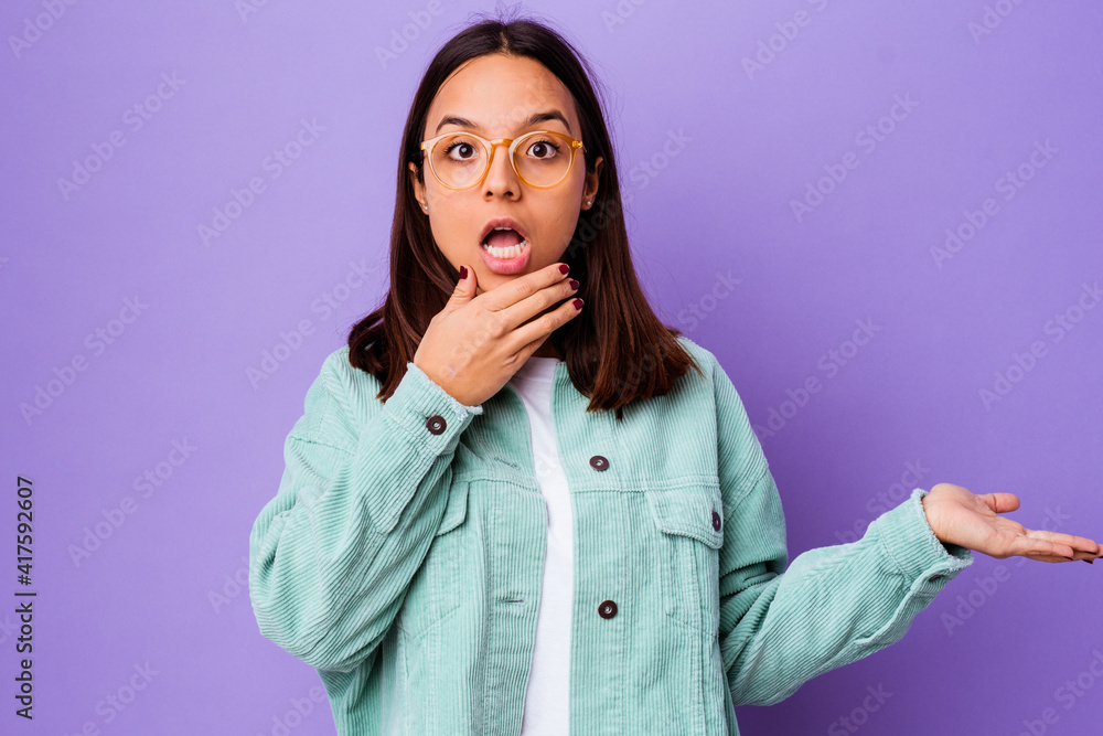 Young mixed race woman isolated holds copy space on a palm, keep hand over cheek. Amazed and delighted. Young mixed race woman isolated holds copy space on a palm, keep hand over cheek. Amazed and delighted.