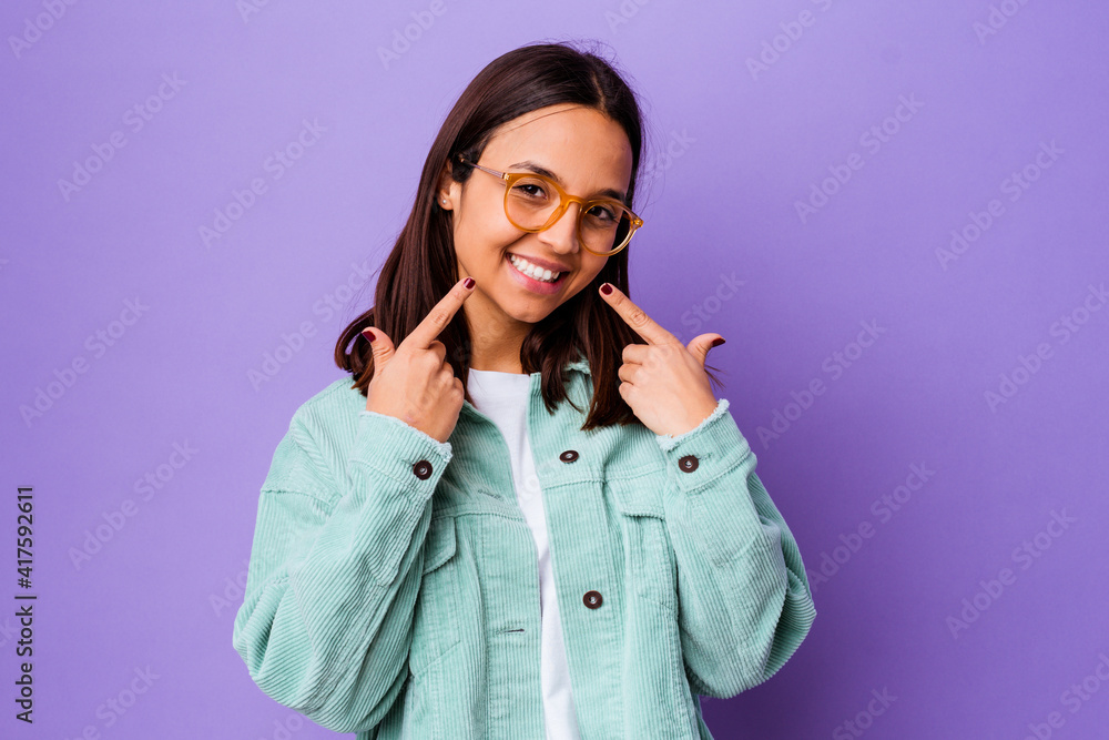 Young mixed race woman isolated smiles, pointing fingers at mouth. Young mixed race woman isolated smiles, pointing fingers at mouth.