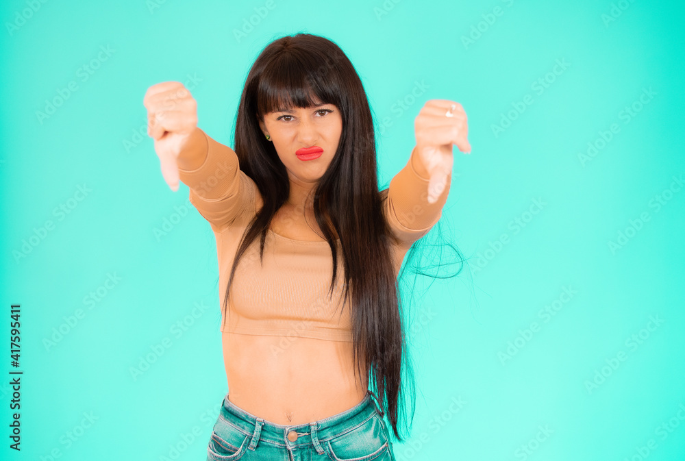 Fototapeta premium Young woman over isolated green background showing thumbs down.