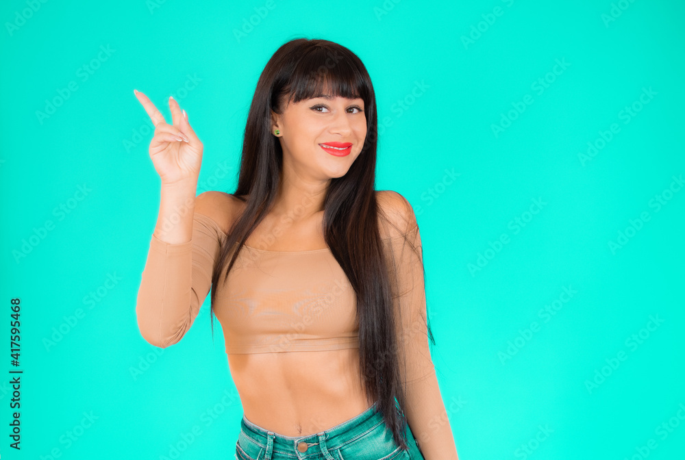 Portrait of a smiling happy woman showing victory sign and looking at camera isolated over green background Portrait of a smiling happy woman showing victory sign and looking at camera isolated over green background
