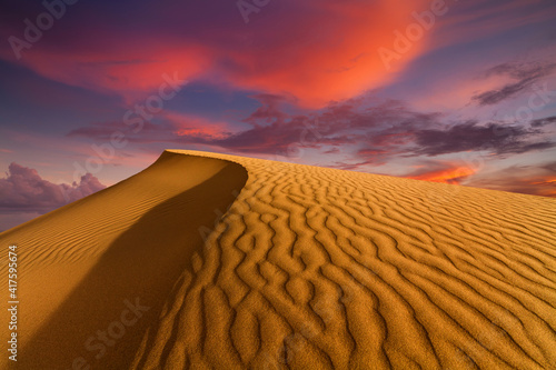 Sunset over the sand dunes in the desert. Arid landscape of the Sahara desert