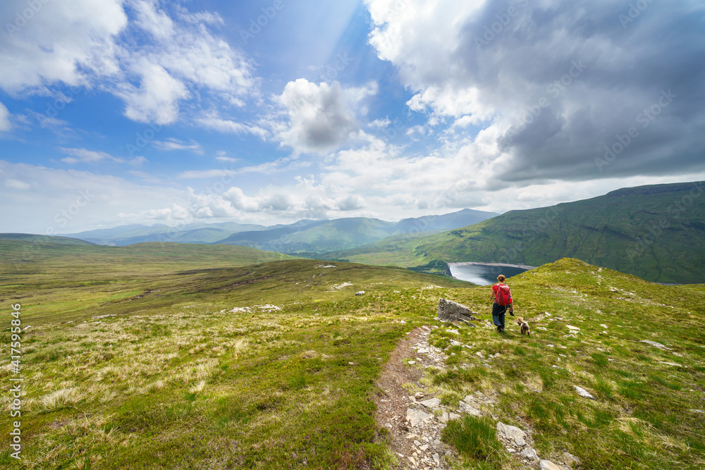 A female hiker descending the summit Meall a Phuill towards Loch an Daimh in the Scottish Highland mountains, UK landscapes. A female hiker descending the summit Meall a Phuill towards Loch an Daimh in the Scottish Highland mountains, UK landscapes.