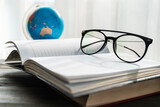 Reading glasses put on open book beside the window