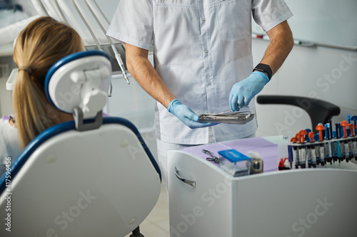 Medical specialist choosing dental tweezers from a tray