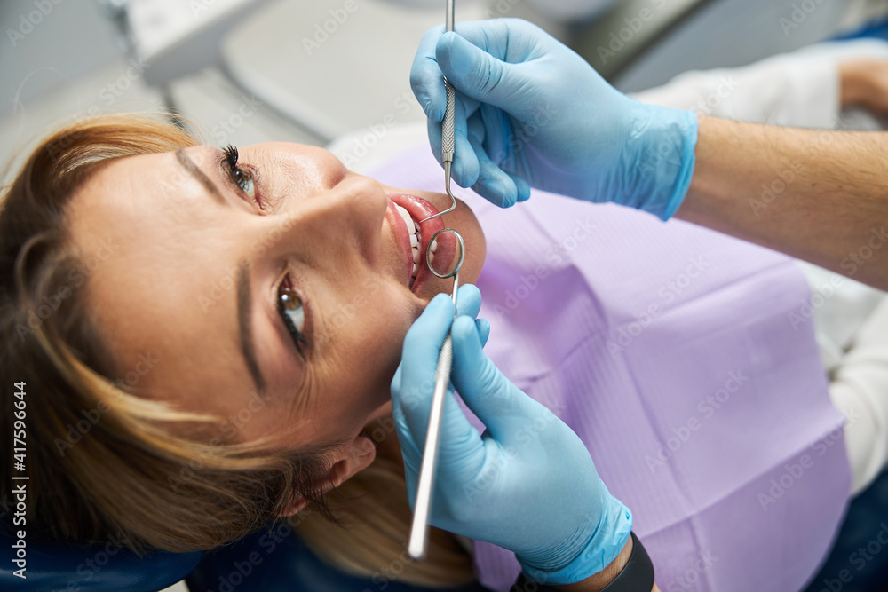 Fototapeta premium Dental mirror and explorer in a female mouth