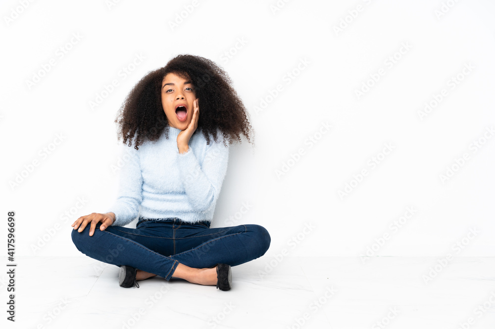 Young african american woman sitting on the floor with surprise and shocked facial expression Young african american woman sitting on the floor with surprise and shocked facial expression