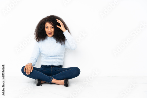 Young african american woman sitting on the floor has just realized something and has intending the solution