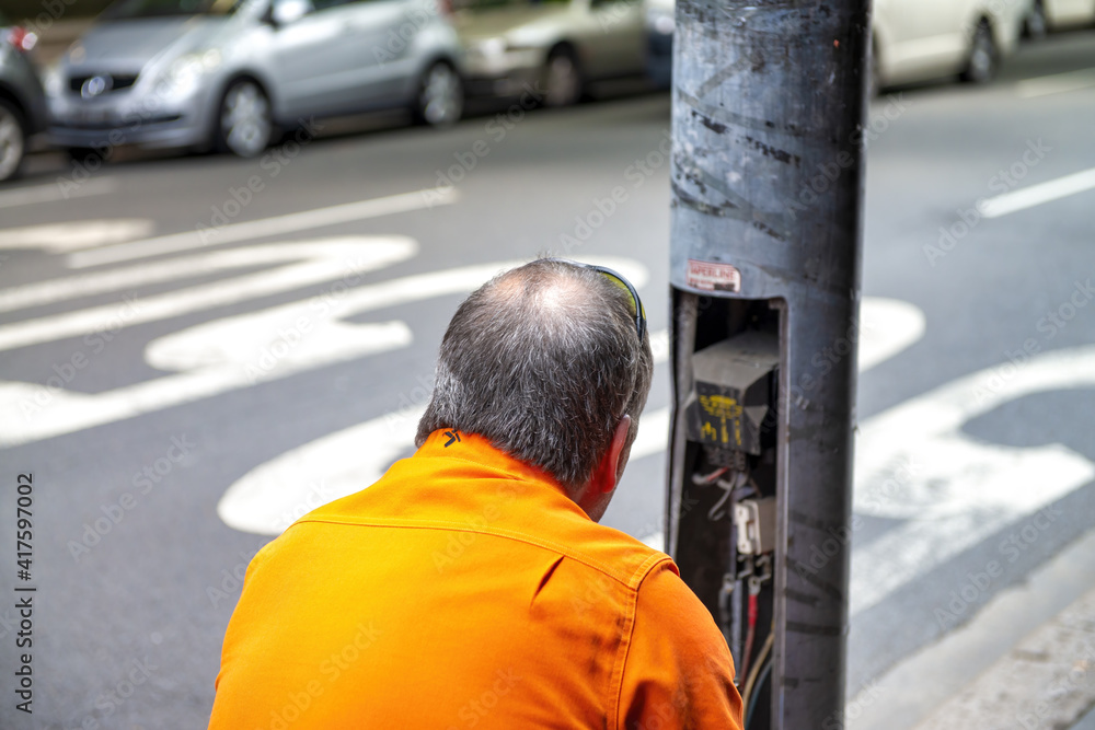 Technician repairs public electrical issue in a street post
