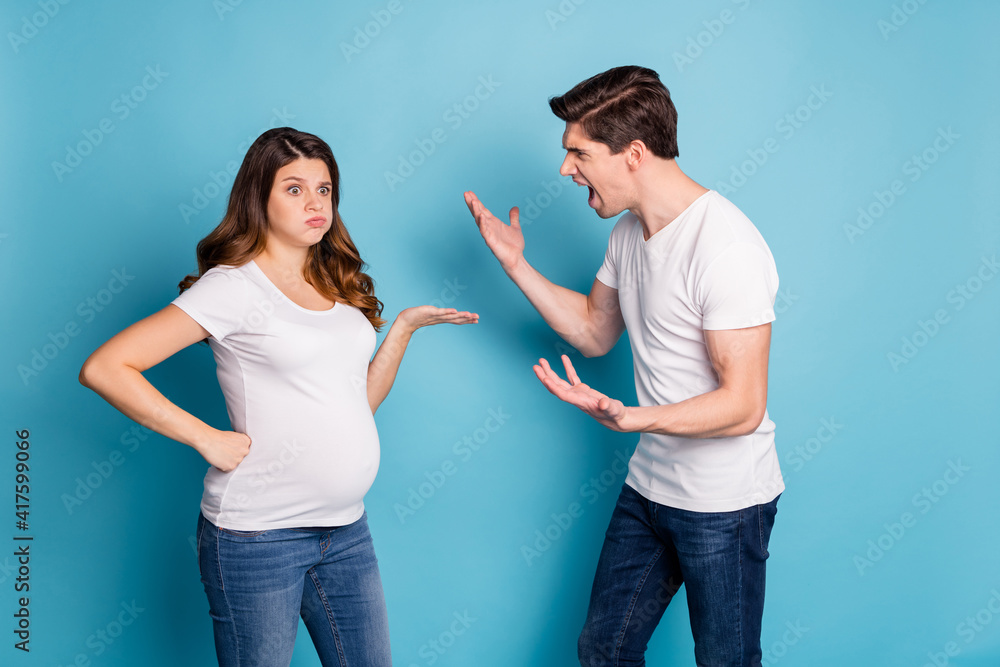 Photo portrait of two people pregnant wife annoyed nervous listening screaming irritated husband isolated bright blue color background Photo portrait of two people pregnant wife annoyed nervous listening screaming irritated husband isolated bright blue color background