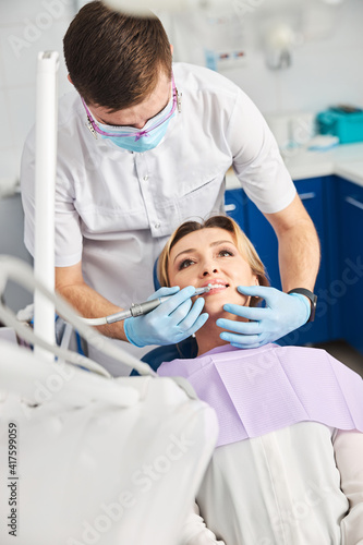 Doctor leaning to a lady during caries removal procedure