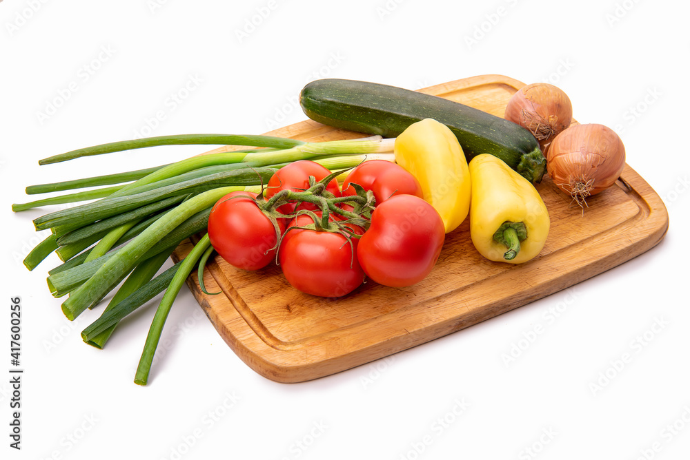 Vegetables on a cutting board. Tomatoes, onions, yellow paprika and zucchini. Isolate on white background Vegetables on a cutting board. Tomatoes, onions, yellow paprika and zucchini. Isolate on white background