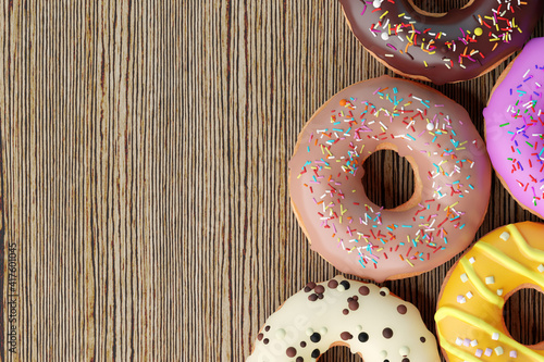 Donuts with colorful icings on wooden background. Sweet background, copy space.  Various glazed doughnuts with colorful sprinkles.