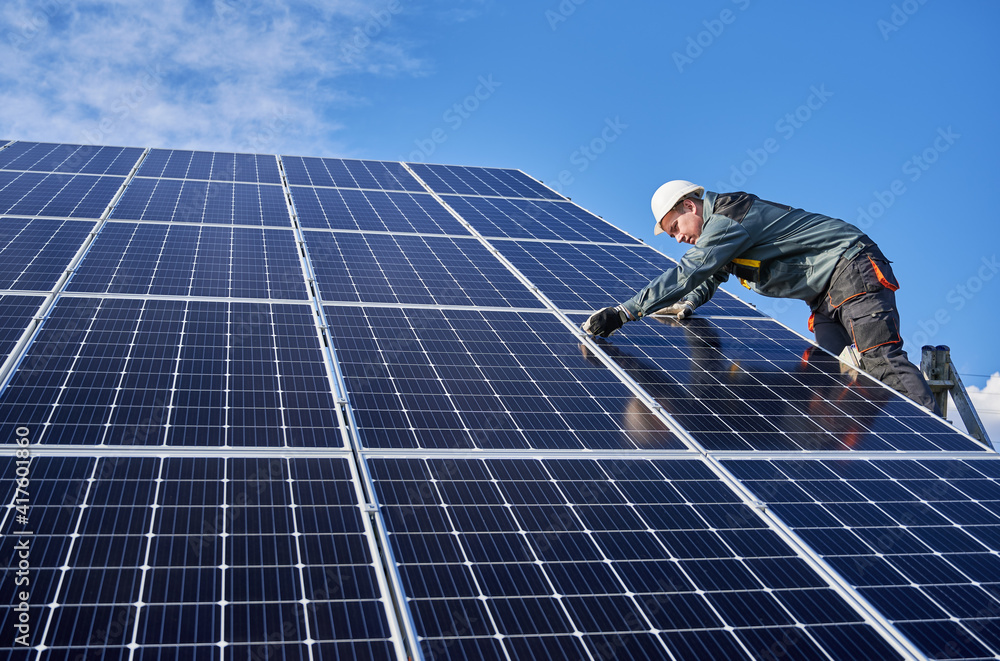 Horizontal snapshot of beautiful and shiny solar battery surface and male  worker wearing a uniform, standing on ladder, installing solar modules on  sunny day, low angle view Stock Photo | Adobe Stock