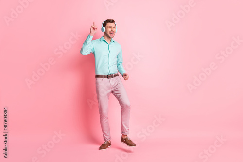 Full size photo of young happy crazy excited cheerful man dancing listen music in headphones isolated on pink color background