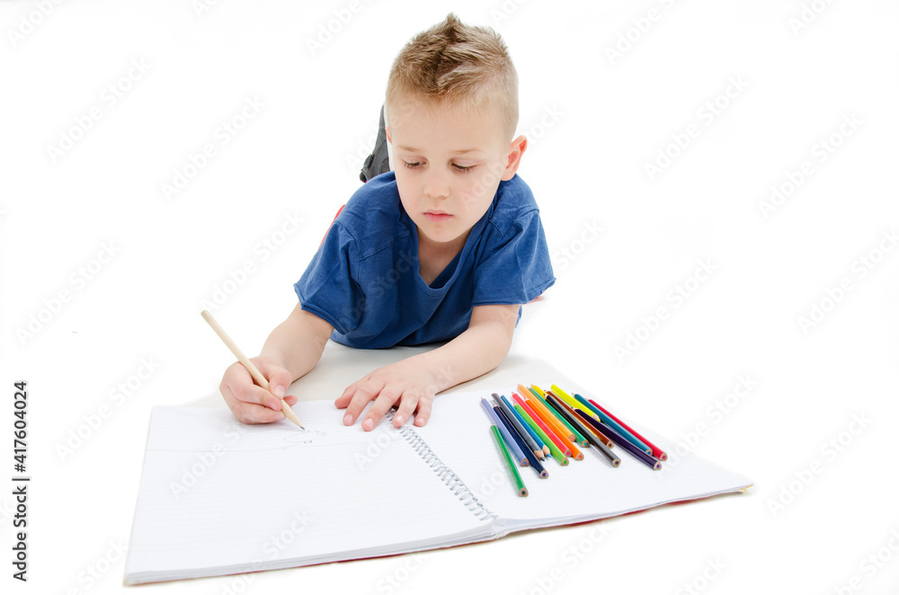 Young boy lying on floor with pencils on a sketch book with a look of concentration, close up view. Isolated on white background
Young boy lying on floor with pencils on a sketch book with a look of concentration, close up view. Isolated on white background