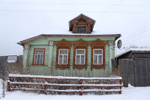 Vintage wooden rural house in Dunilovo village in Ivanovo region, Russia. Building facade; ornamental windows with carved frames. Russian traditional national folk style in architecture. Countryside photo