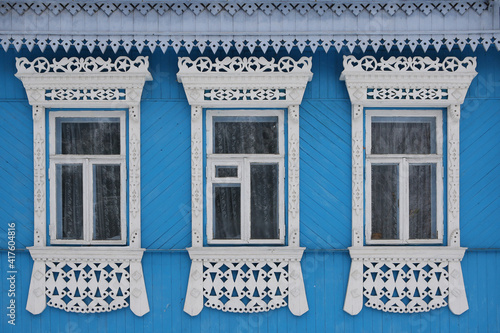 Ornamental windows with carved frames on vintage blue wooden rural house. Dunilovo village, Ivanovo region, Russia. Building facade. Russian traditional national folk style in old wooden architecture photo