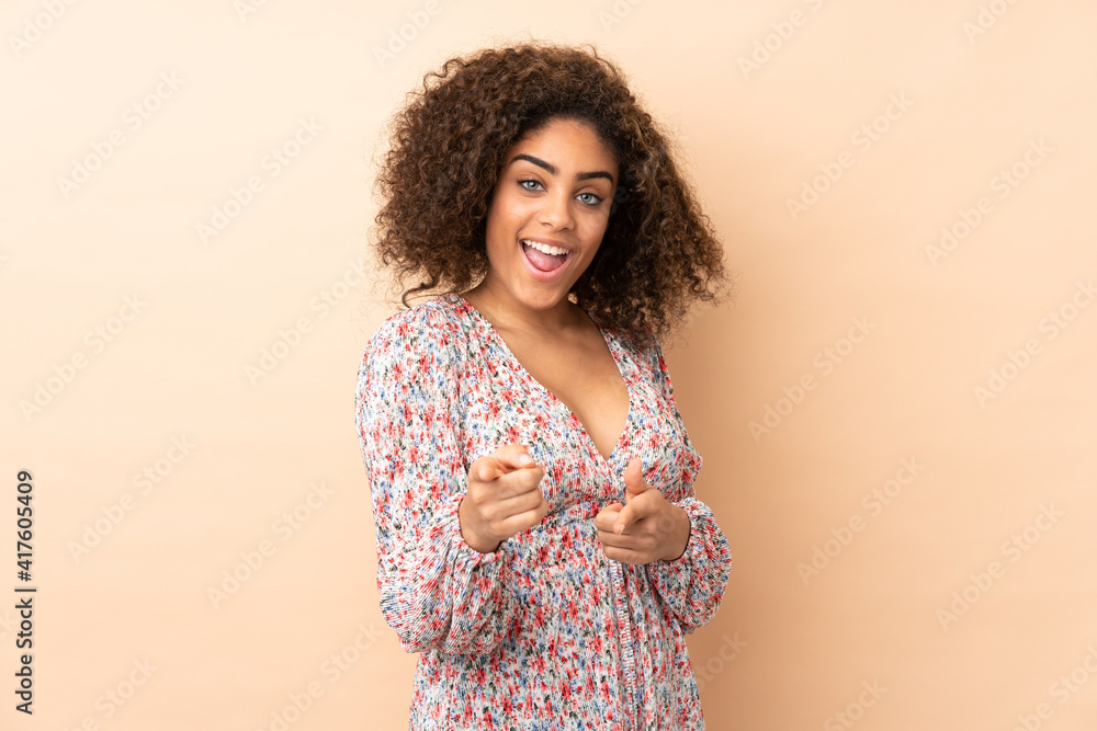 Young African American woman isolated on beige background pointing to the front and smiling Young African American woman isolated on beige background pointing to the front and smiling